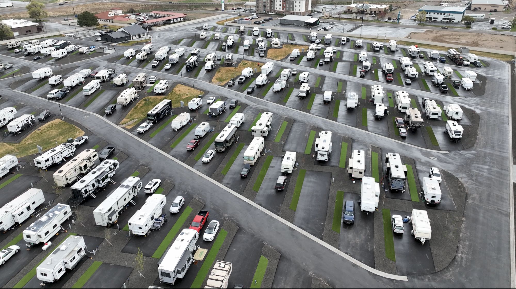 Aerial view of a large RV and camper lot, with rows of mobile homes and trailers parked on neat lots and winding streets&mdash;busier than typical.