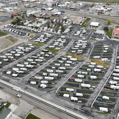An aerial view of a large RV/van storage lot with rows of parked campers and trailers, roads weaving through the grid-like area.